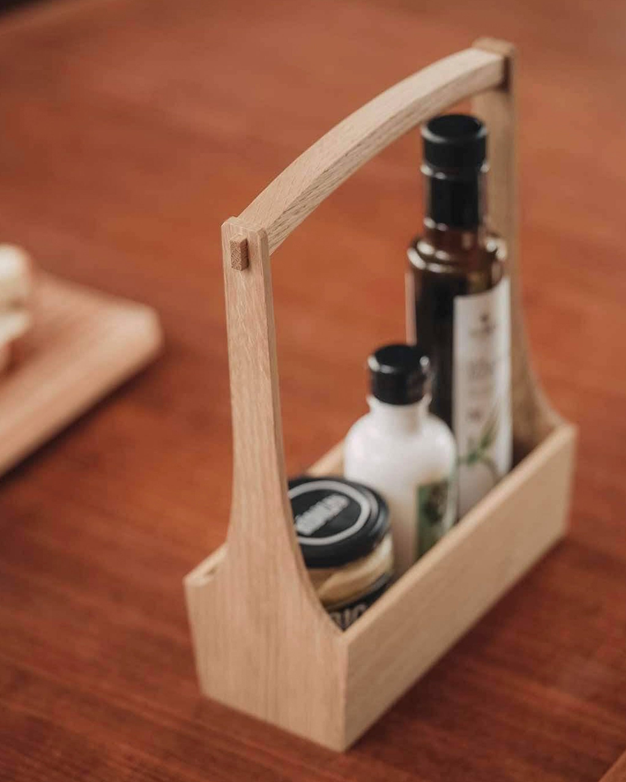 Wooden table caddy with long handle by Aizawa, holding various bottles on a wooden surface