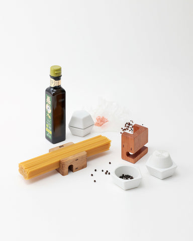 Collection of kitchen items including an oil bottle, wooden holders, and spice mill containers with black pepper on a white background