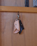 Two small Circle Cut Out Key Chains in nataural and black by Hender Scheme and Artek hanging on a hook with a wooden backdrop