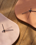 Two corners of Leather Clock by Hender Scheme on a wooden background