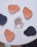 Coasters by Hender Scheme and Artek on table with a glass on one