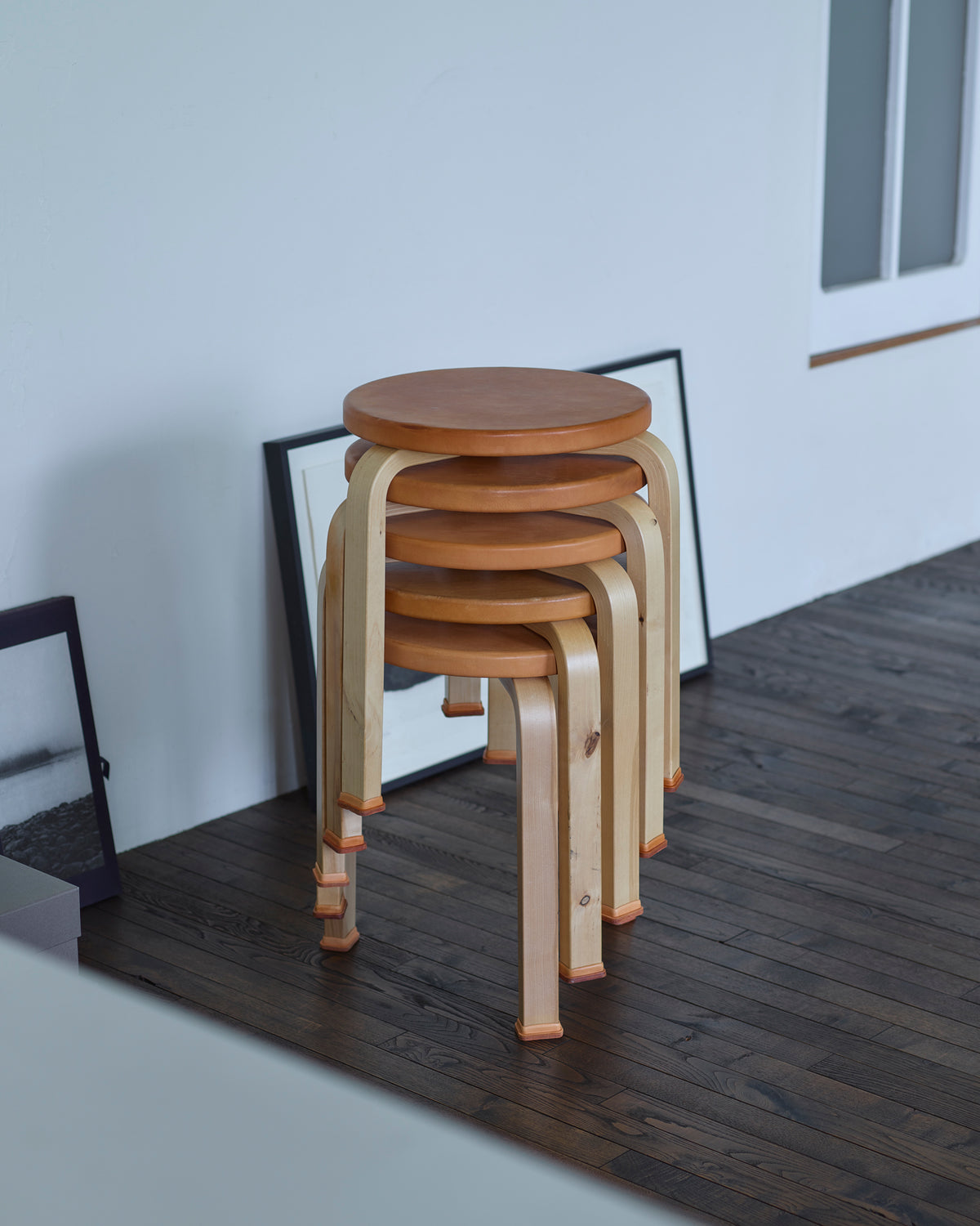 Stacked aged stools with shoes by Artek and Hender Scheme in a room