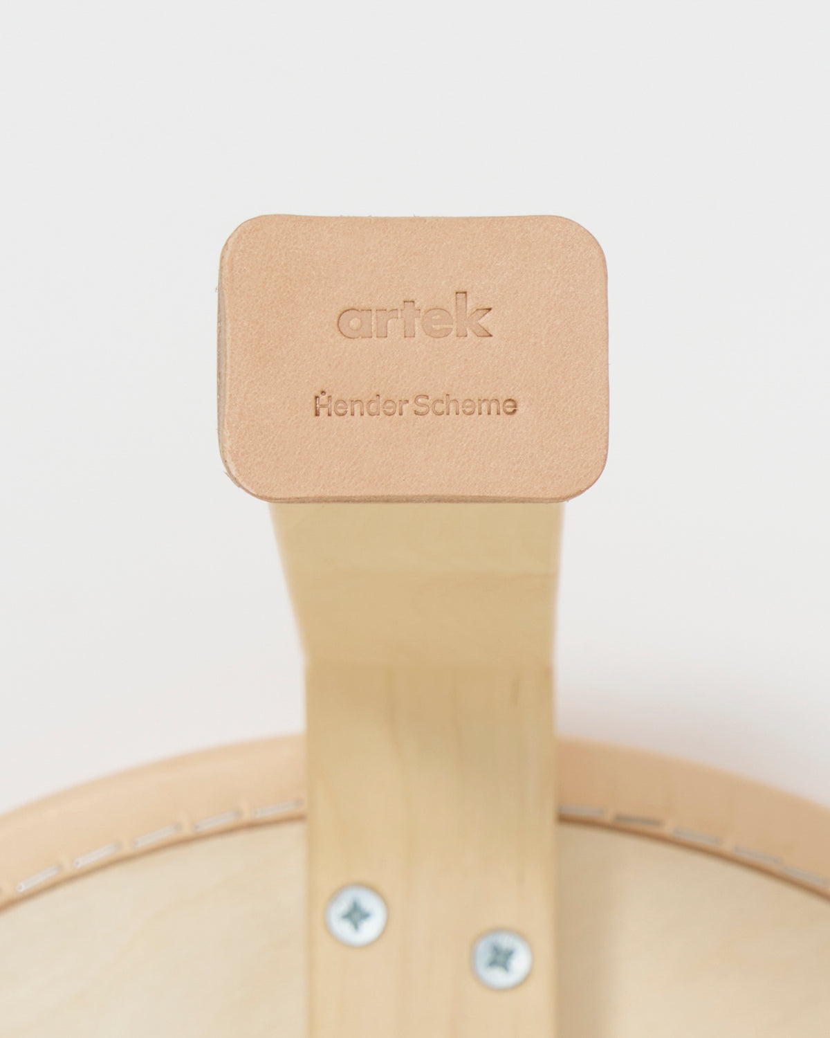 Up-close of stool leg with shoes by Artek and Hender Scheme on a gray background