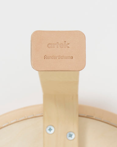 Up-close of stool leg with shoes by Artek and Hender Scheme on a gray background