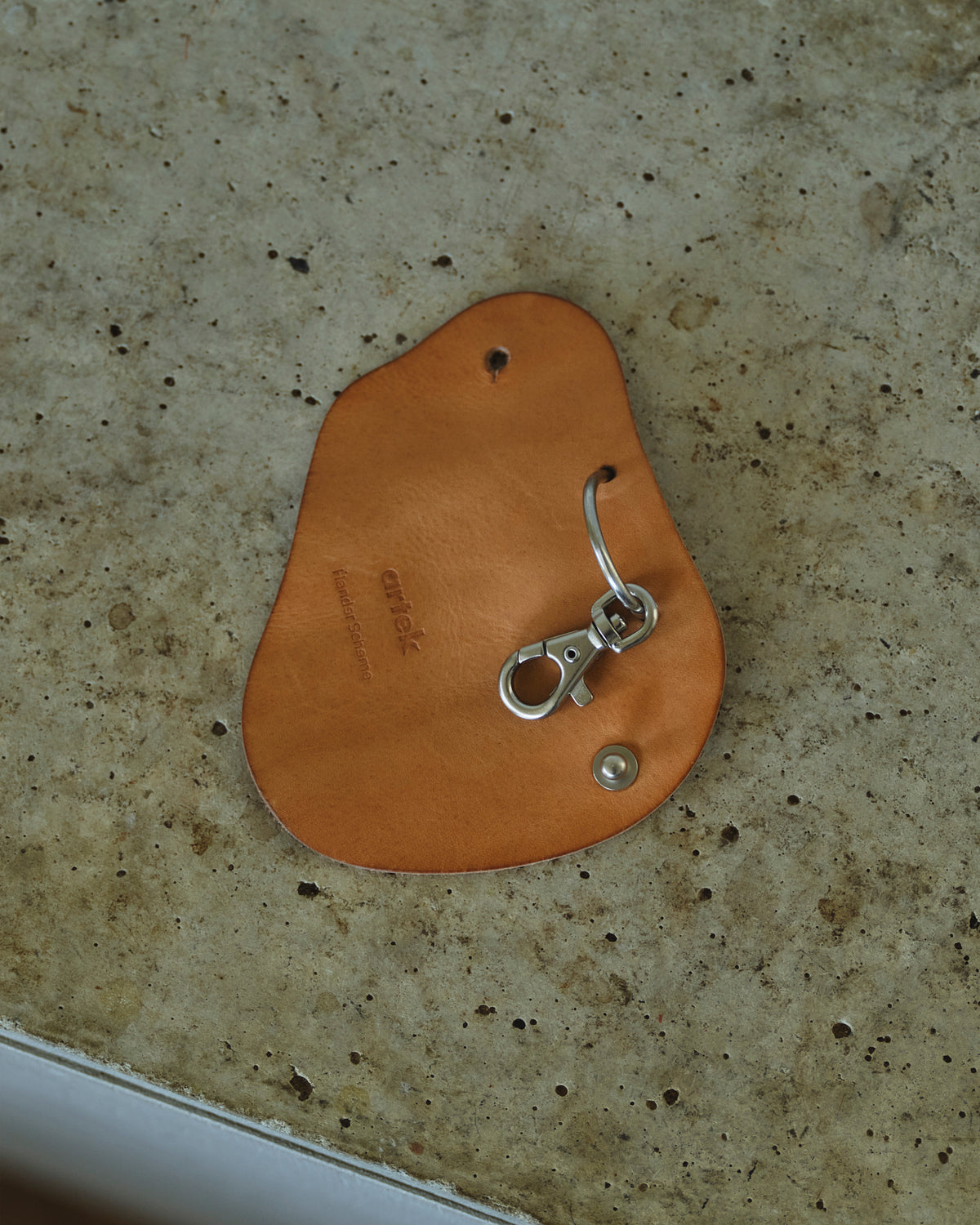 Opened Circle Cut Out Key Chain by Hender Scheme and Artek on a concreate background