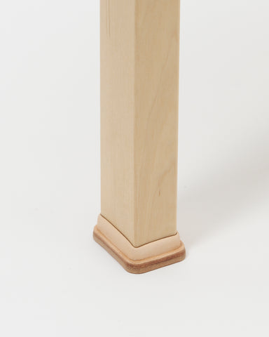 Up-close of stool with shoes by Artek and Hender Scheme on a gray background