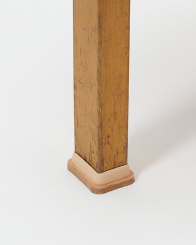 Up-close of aged stool foot wearing leather shoe by Artek and Hender Scheme on a  gray background