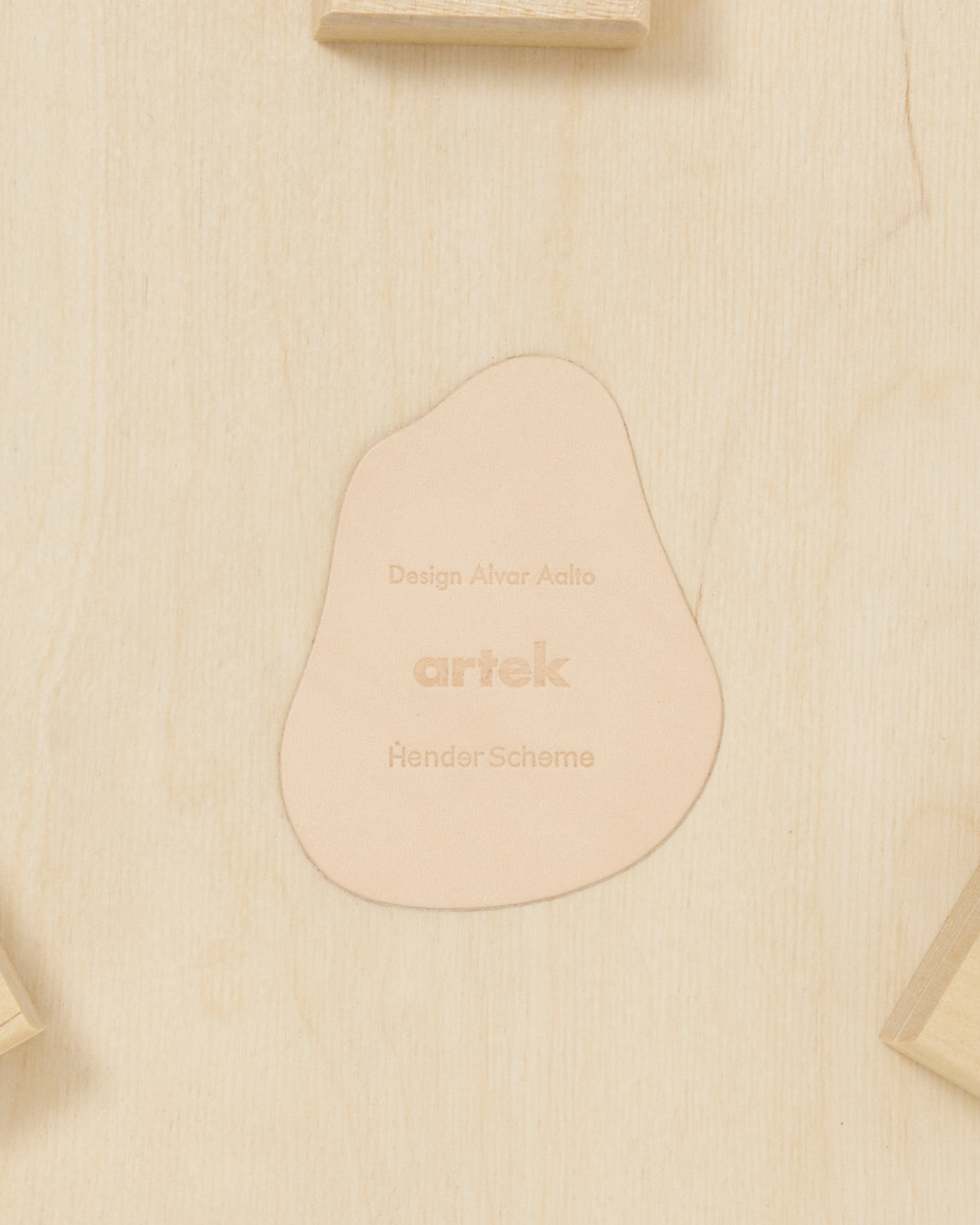Up-close of backside of stool with shoes by Artek and Hender Scheme on a gray background