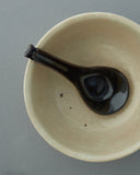 In situation image of black Ceramic Soup Spoon by Azmaya in cream ceramic bowl.