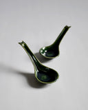 Front view of 2 staggered oribe green Ceramic Soup Spoons by Azmaya against white-gray background. 