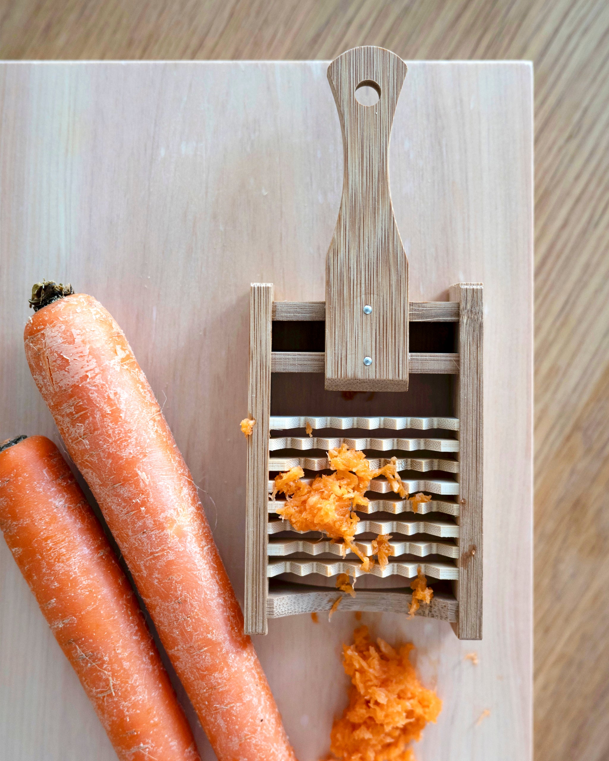 Bamboo Daikon Grater by Kohchosai Kosuga in Small size on a cutting board with carrots and grated carrots