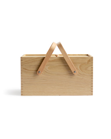 Silhouetted image of chestnut wood picnic box featuring wood joinery on edges with handles standing up by Shinsuke Tanabe against white background.