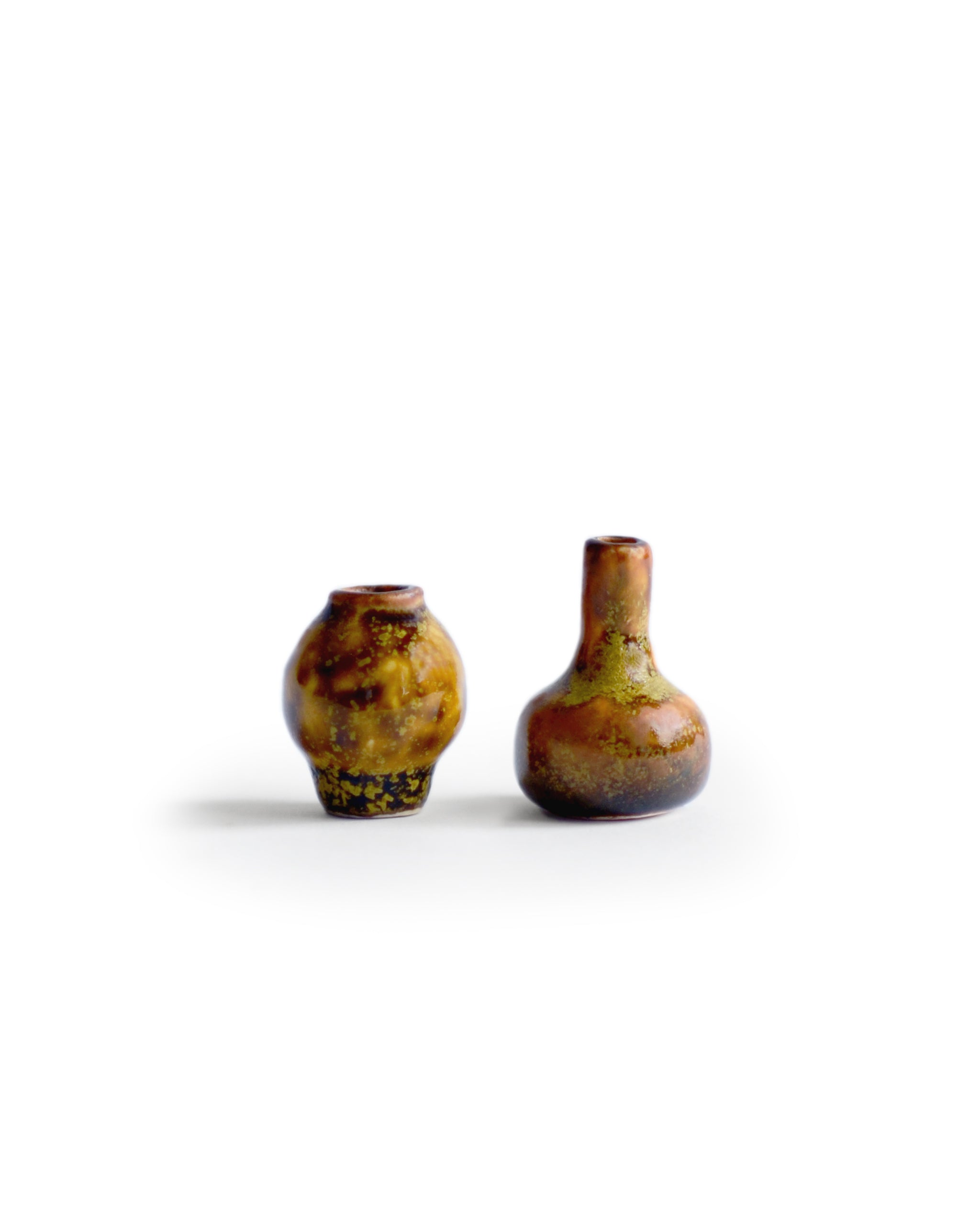  Silhouetted image of 2 brown glazed mini vases from the Mini Vase Set -Duo II by Dani Sujin x Nalata Nalata against white background.