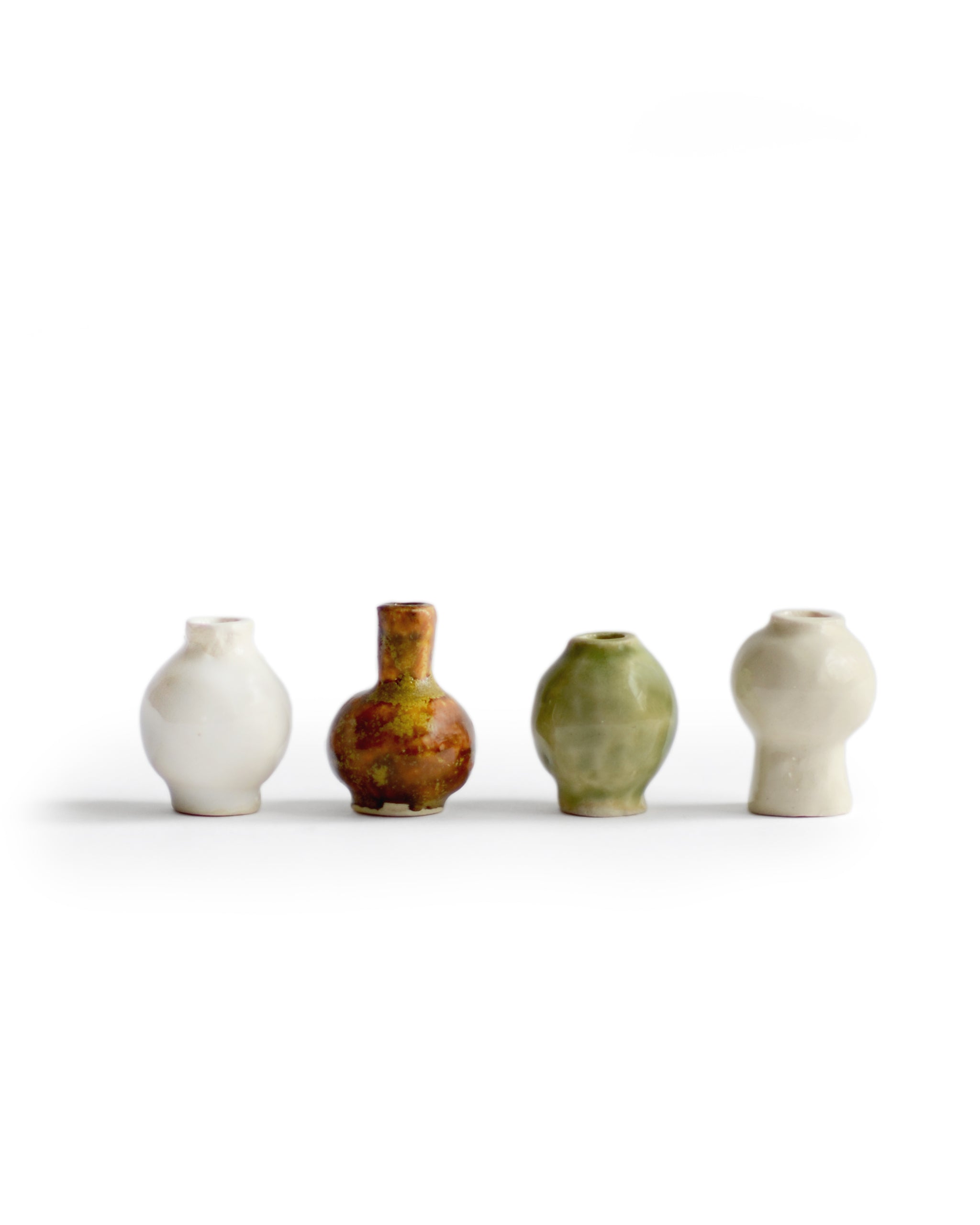  Silhouetted image of  mini white, brown, green, and cream glazed mini vases from the Mini Vase Set - Quad by Dani Sujin x Nalata Nalata against white background.