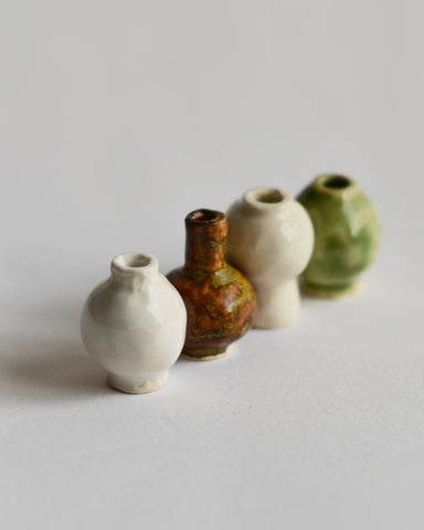 Image of  mini white, brown, green, and cream glazed mini vases lined up at an angle from the Mini Vase Set - Quad by Dani Sujin x Nalata Nalata against white-gray background.