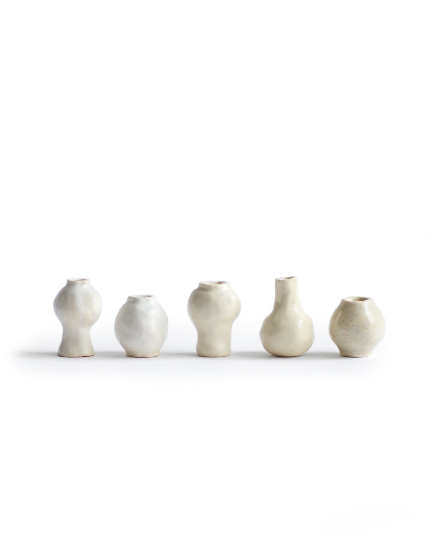 Silhouetted image of 5 varying mini white and cream glazed mini vases from the  Mini Vase Set - Quint by Dani Sujin x Nalata Nalata against white background.