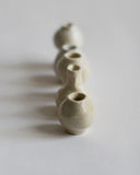 Image of 5 varying mini white and cream glazed mini vases in a receding straight line from the Mini Vase Set - Quint by Dani Sujin x Nalata Nalata against white-gray background.