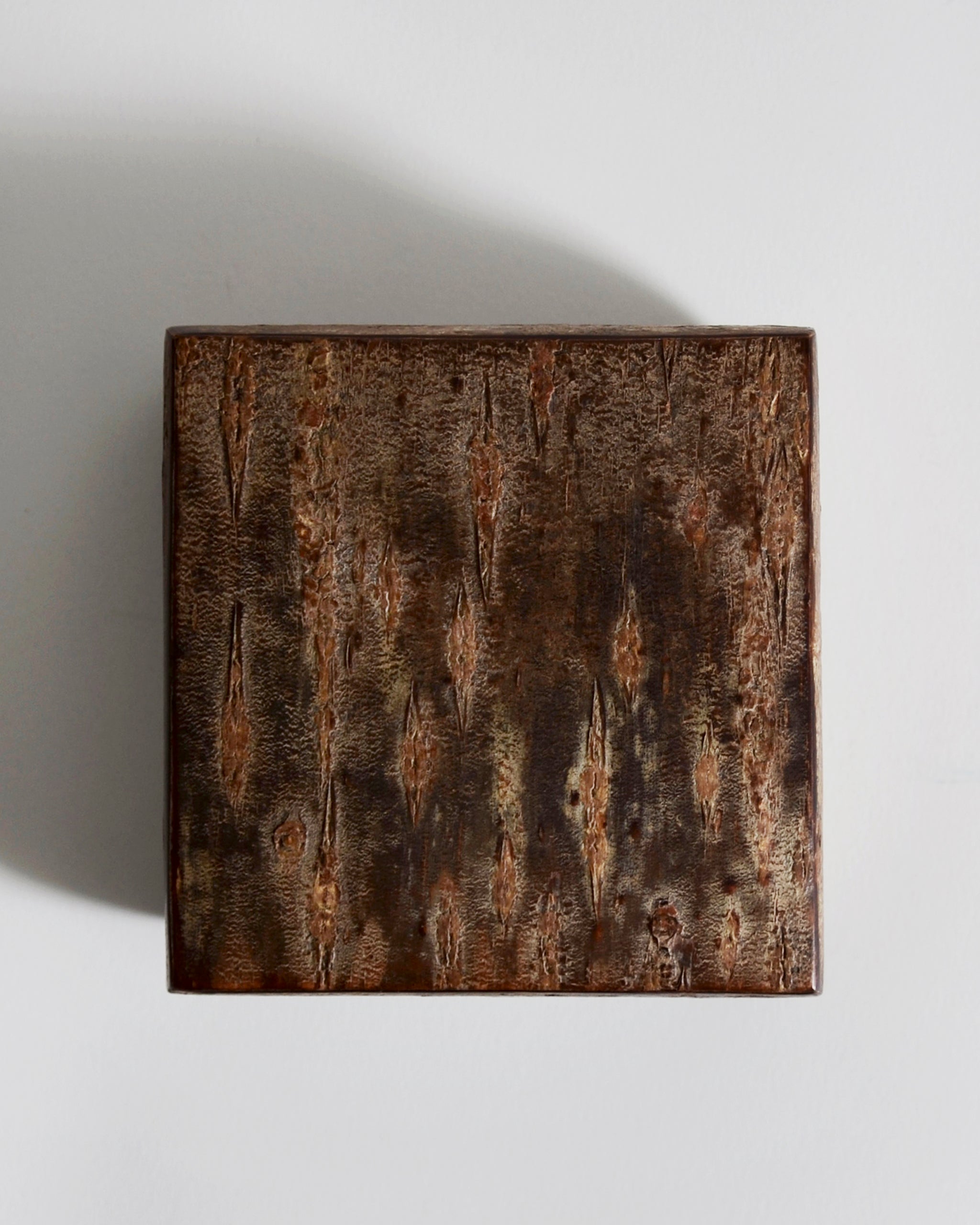 Top view of square wooden box with a textured surface by Denshiro on a light gray background