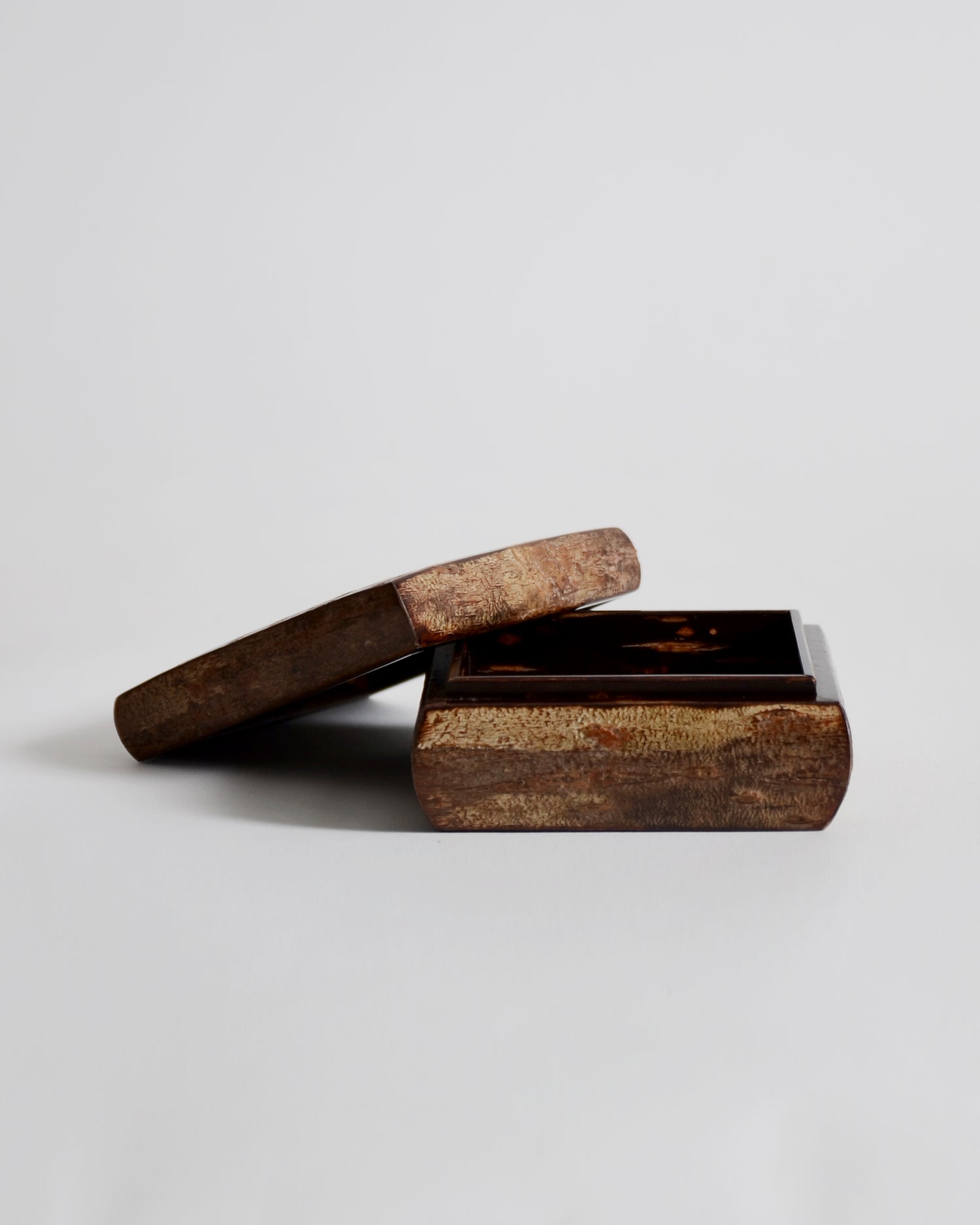 Opened wooden box by Denshiro with a lid laid on its side on a light gray background