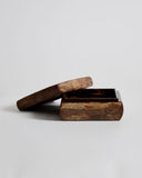 Opened wooden box by Denshiro with a lid laid on its side on a light gray background