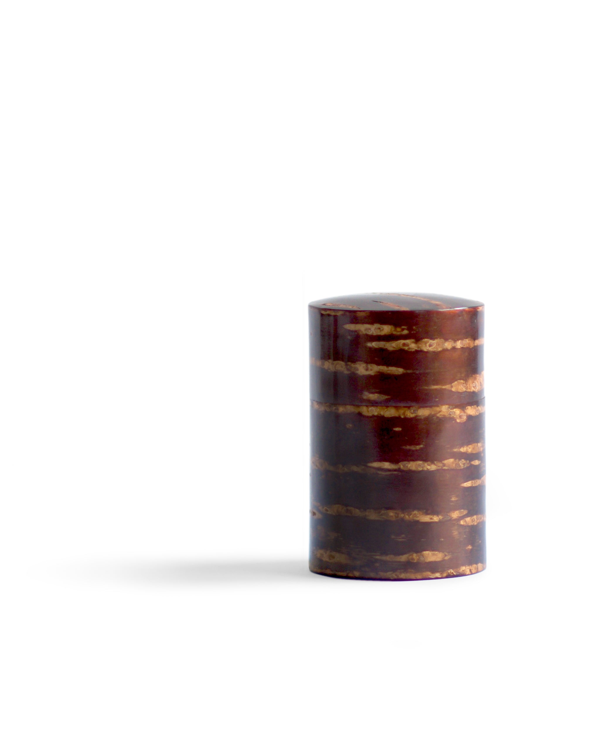 Off center silhouetted image of narrow Smooth Cherry Bark Tea Canister by Denshiro against white background.
