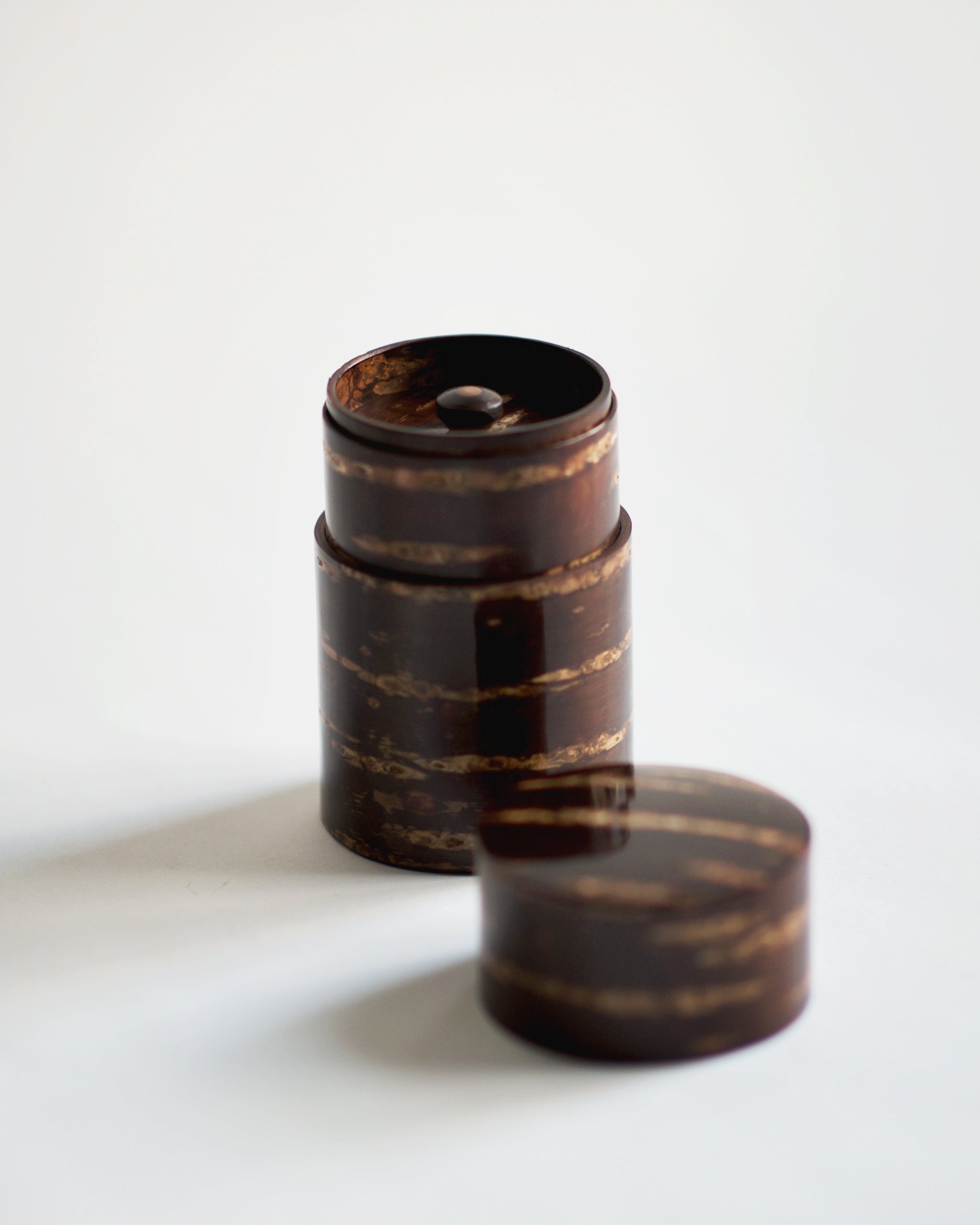 Image of open narrow Smooth Cherry Bark Tea Canister by Denshiro against white-gray background with lid placed infront.