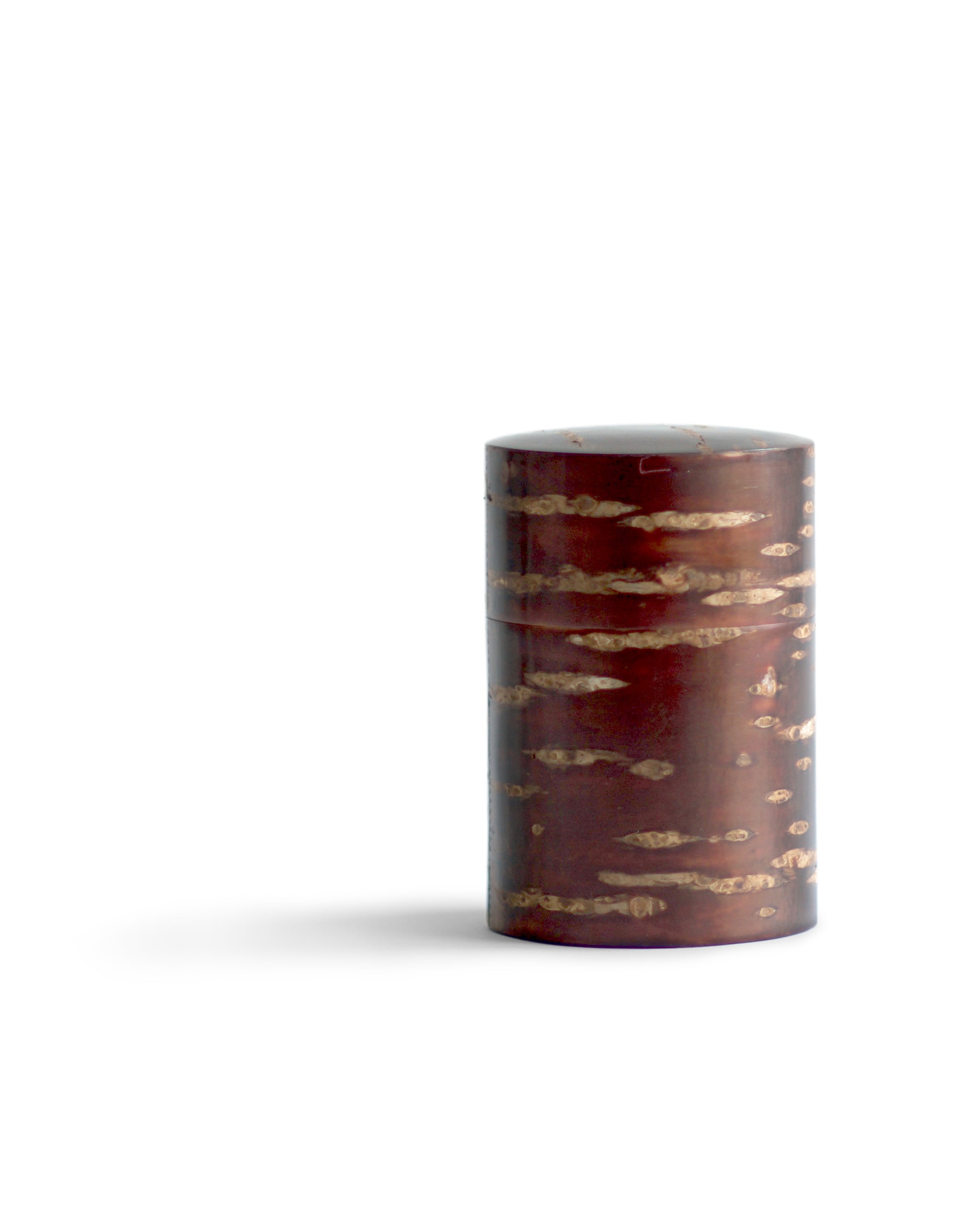 Off center silhouetted image of tall Smooth Cherry Bark Tea Canister by Denshiro against white background.