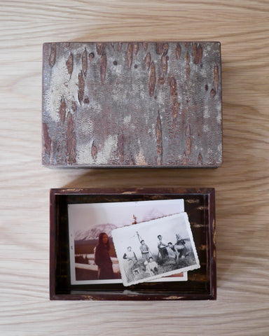Open wooden box with vintage family photos in the interior and lid by Denshiro on a wooden surface