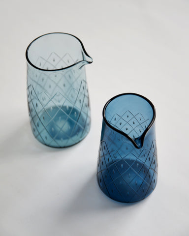 Two wire net one lipped pitchers next to each other. One on the left is lighter blue and the one on the right is dark blue.