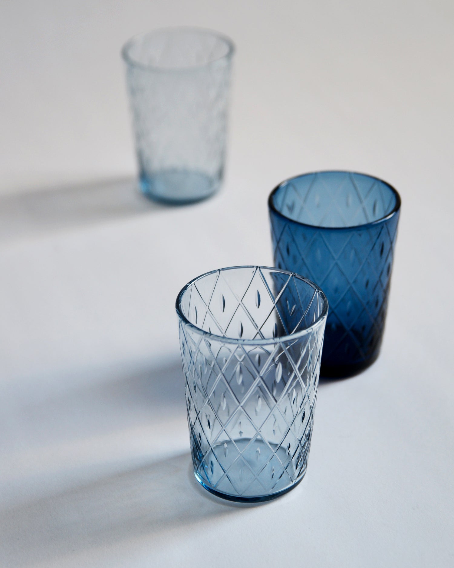 Three wire net ordinary cup in a diagonal row. Each cup is of a different shade of blue.