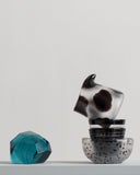 Pieces that are part of the relife composition no.1 are set on top of the box shelf. The pieces include reclaimed blue jewelry cut paperweight, carved bowl, two mini-choko glasses, and a cow pitcher.