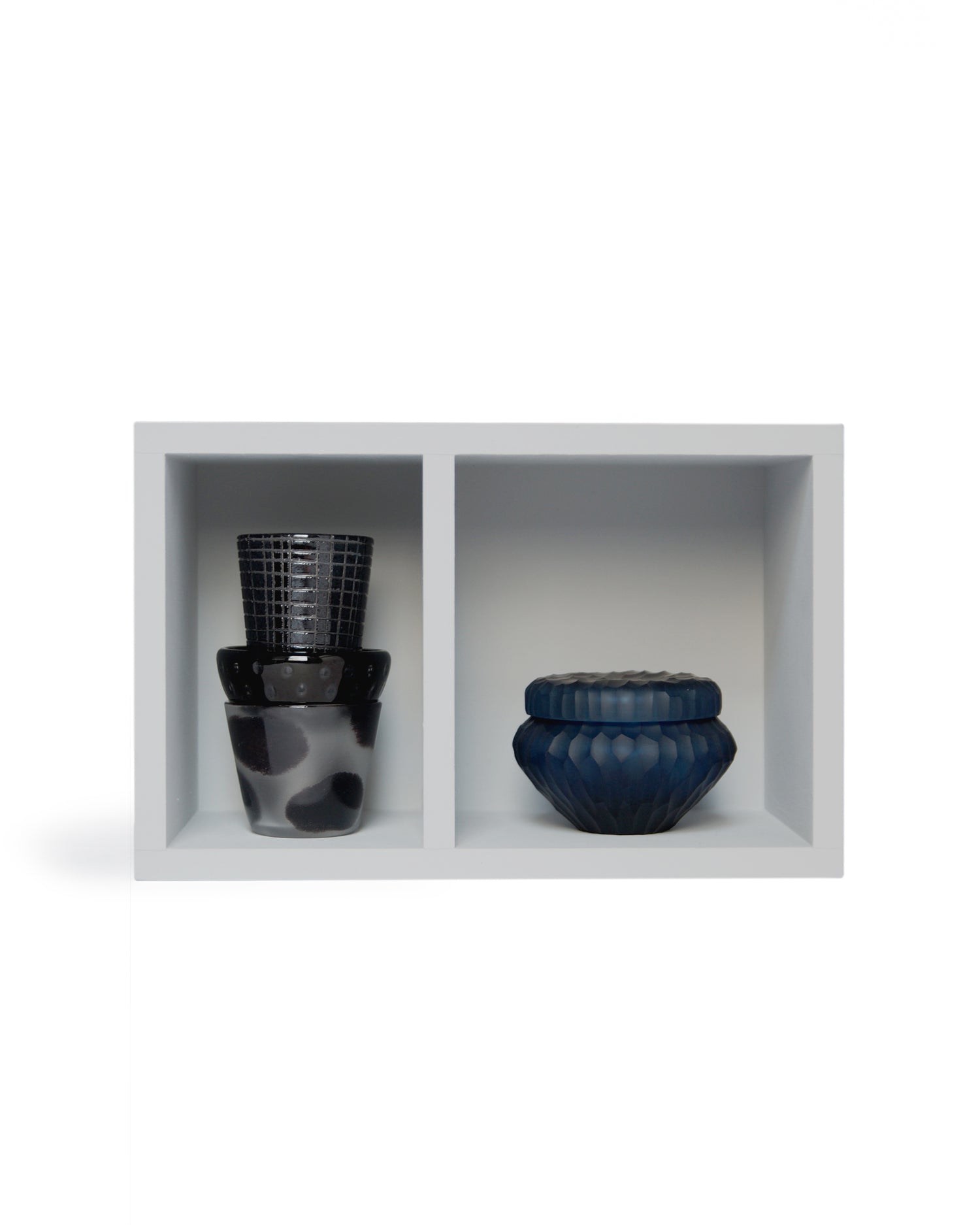 Silhouetted image of relife composition no.2. The left compartment of the gray container box contains stacked mini choko, mini maru, and shot glass. The right compartment has the reclaimed blue container.