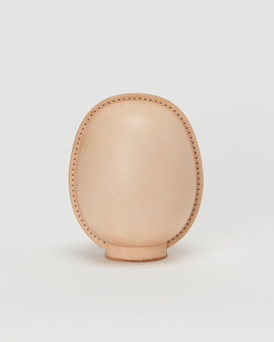 Back view of large leather Daruma doll by Hender Scheme in on  a gray background
