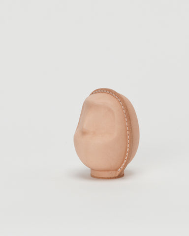 Side view of large leather Daruma doll by Hender Scheme in on  a gray background