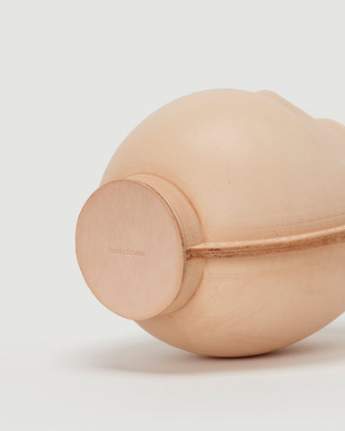 Bottom view of large leather Daruma doll by Hender Scheme in on  a gray background