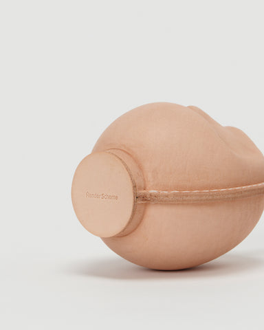Bottom view of small leather Daruma doll by Hender Scheme in on  a gray background