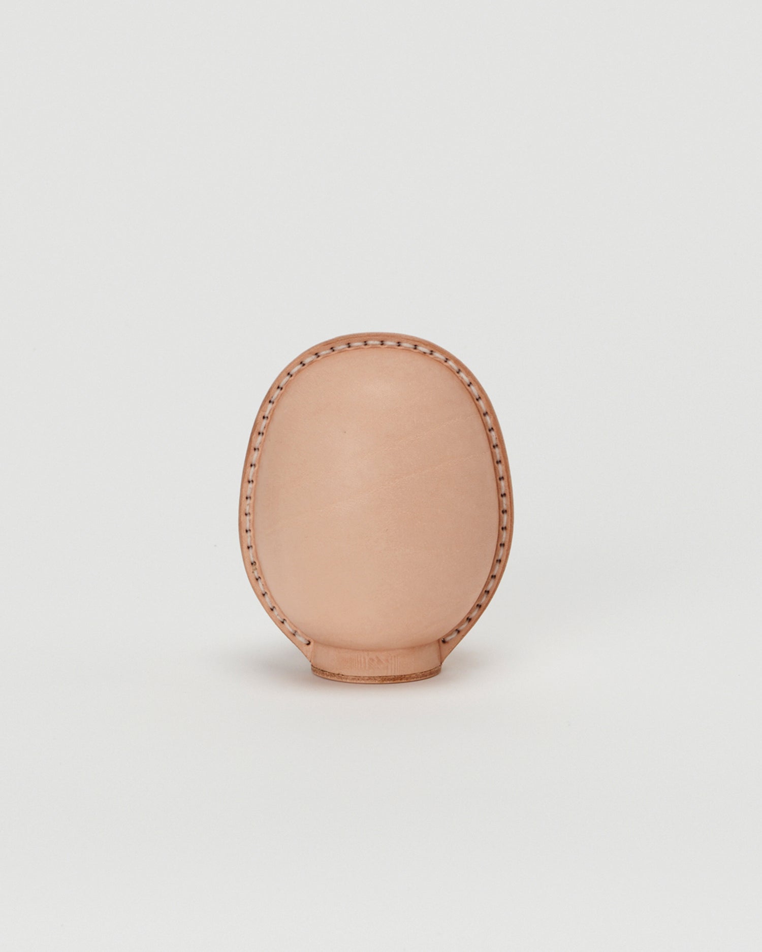 Back view of small leather Daruma doll by Hender Scheme in on  a gray background