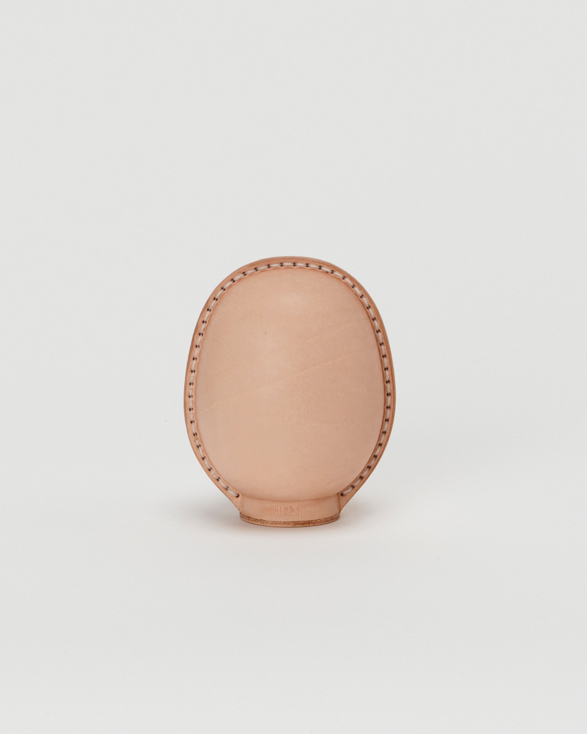 Back view of small leather Daruma doll by Hender Scheme in on  a gray background