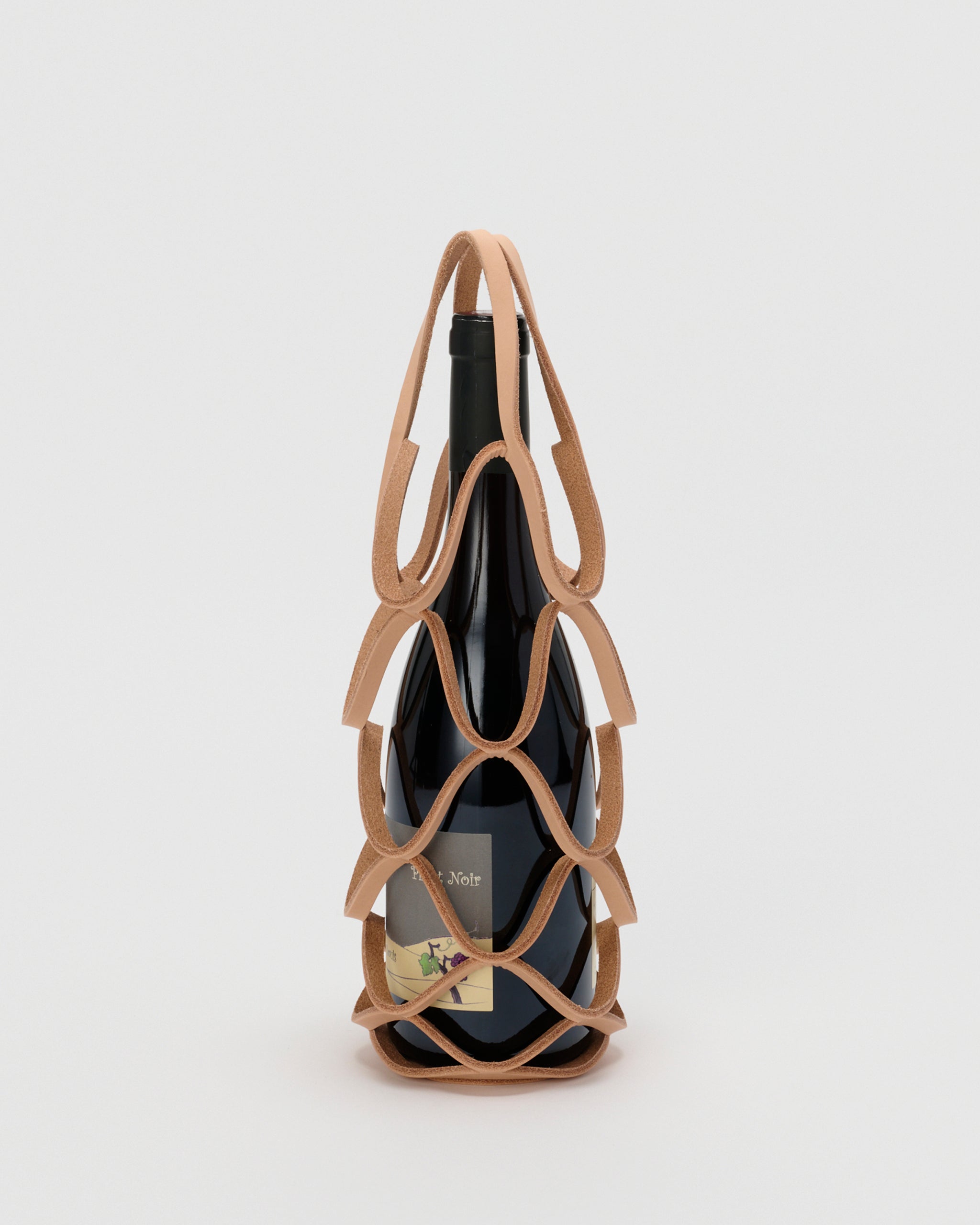 Wine bottle in wine holder by Hender Scheme with a gray background