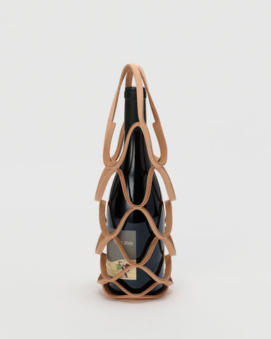 Wine bottle in wine holder by Hender Scheme with a gray background