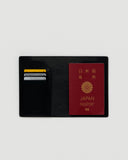 Open Black leather Passport Case by Hender Scheme on a gray background
