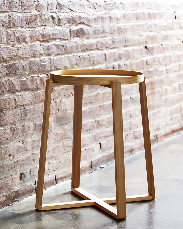 Hinoki Magewa Tray Table 450 is placed on a gray cement floor and infront of red brick wall.