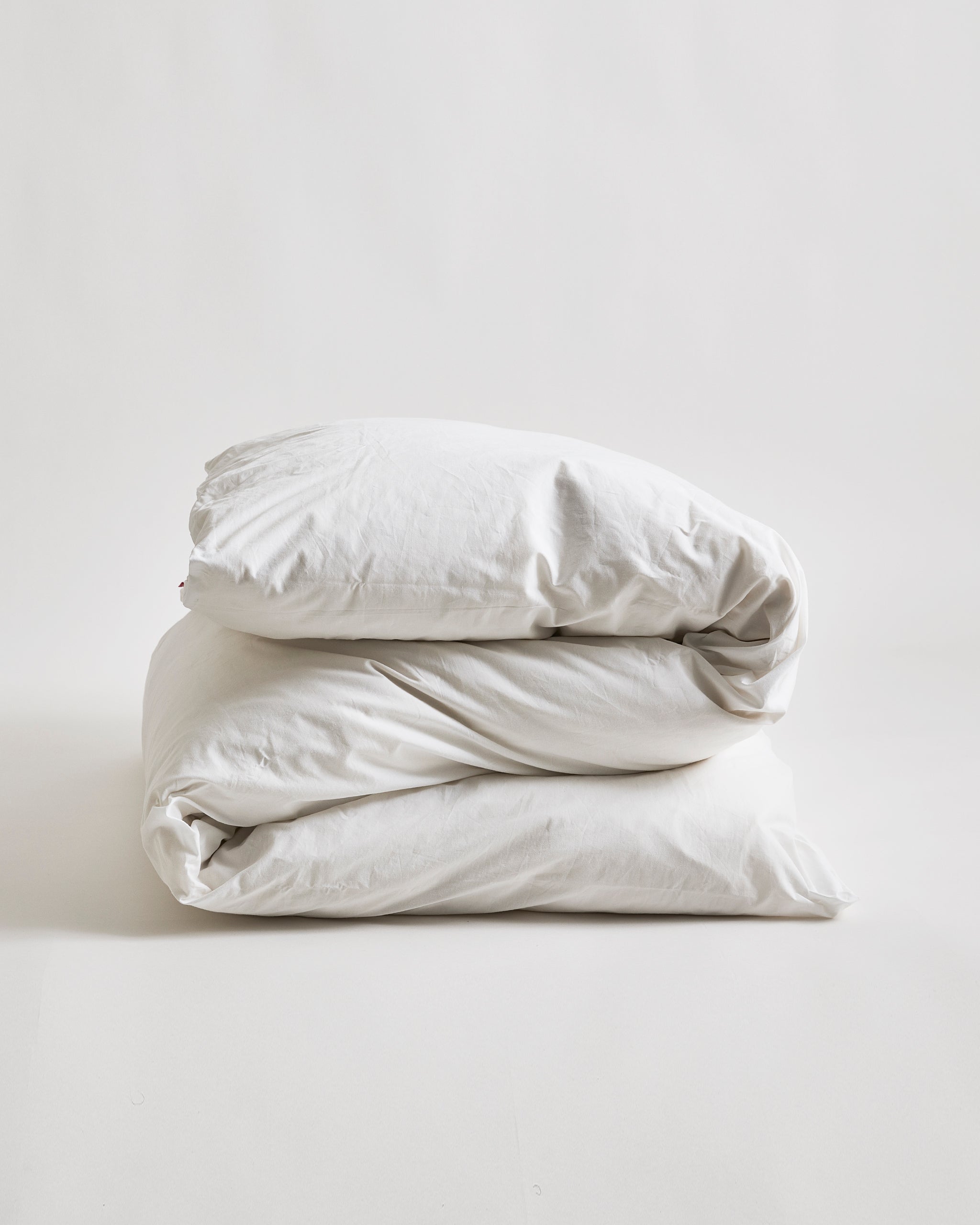 Folded white duvet cover on a duvet by Iwata on a gray background