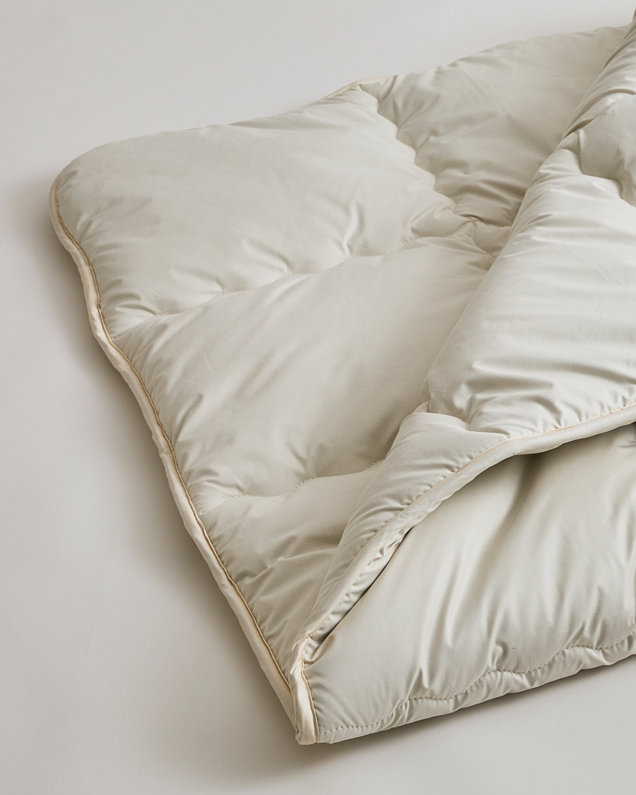 Up-close of Camel Heavy Mattress Pad by Iwata on a gray background