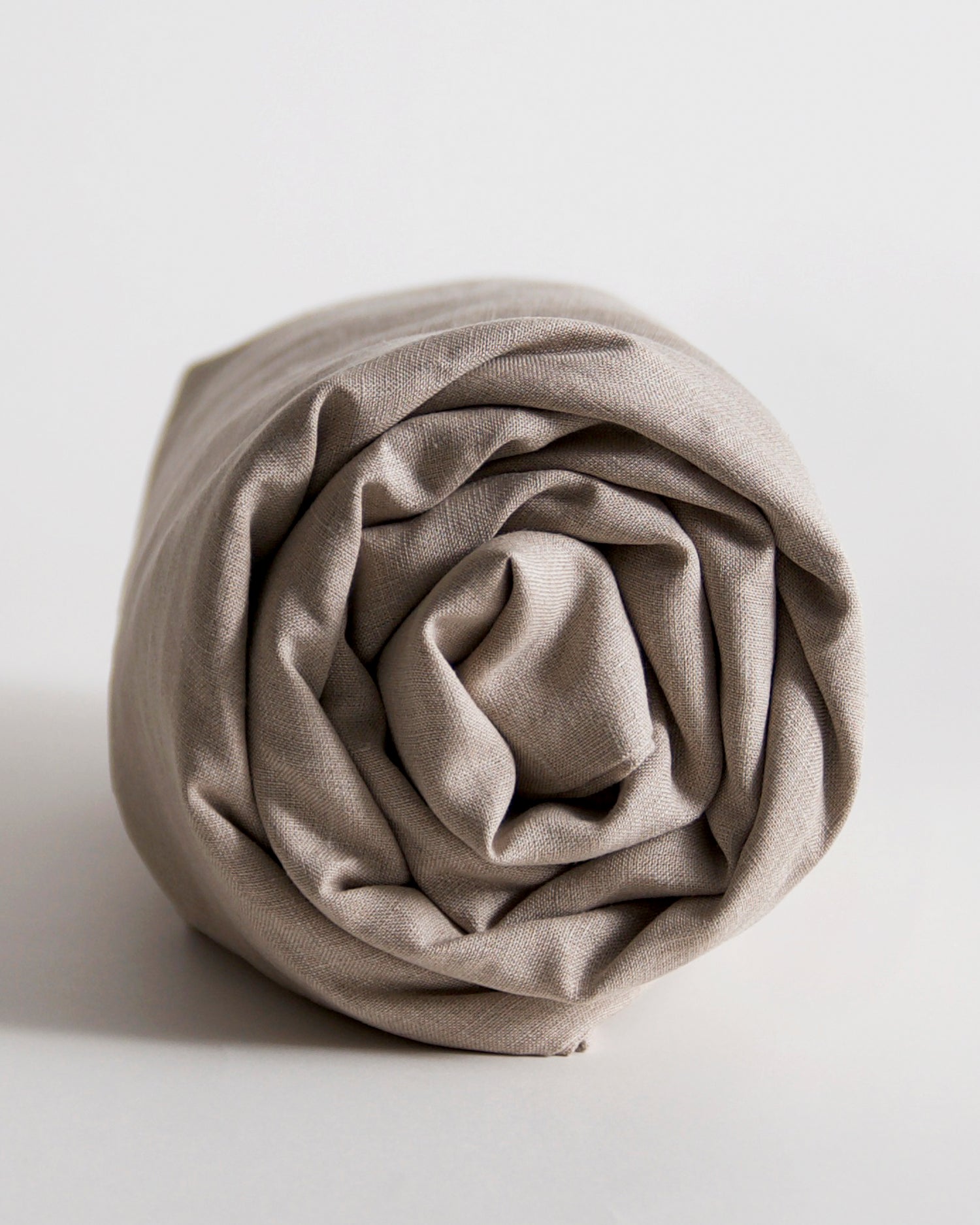 Rolled-up unbleached linen duvet cover by iwata on a gray background