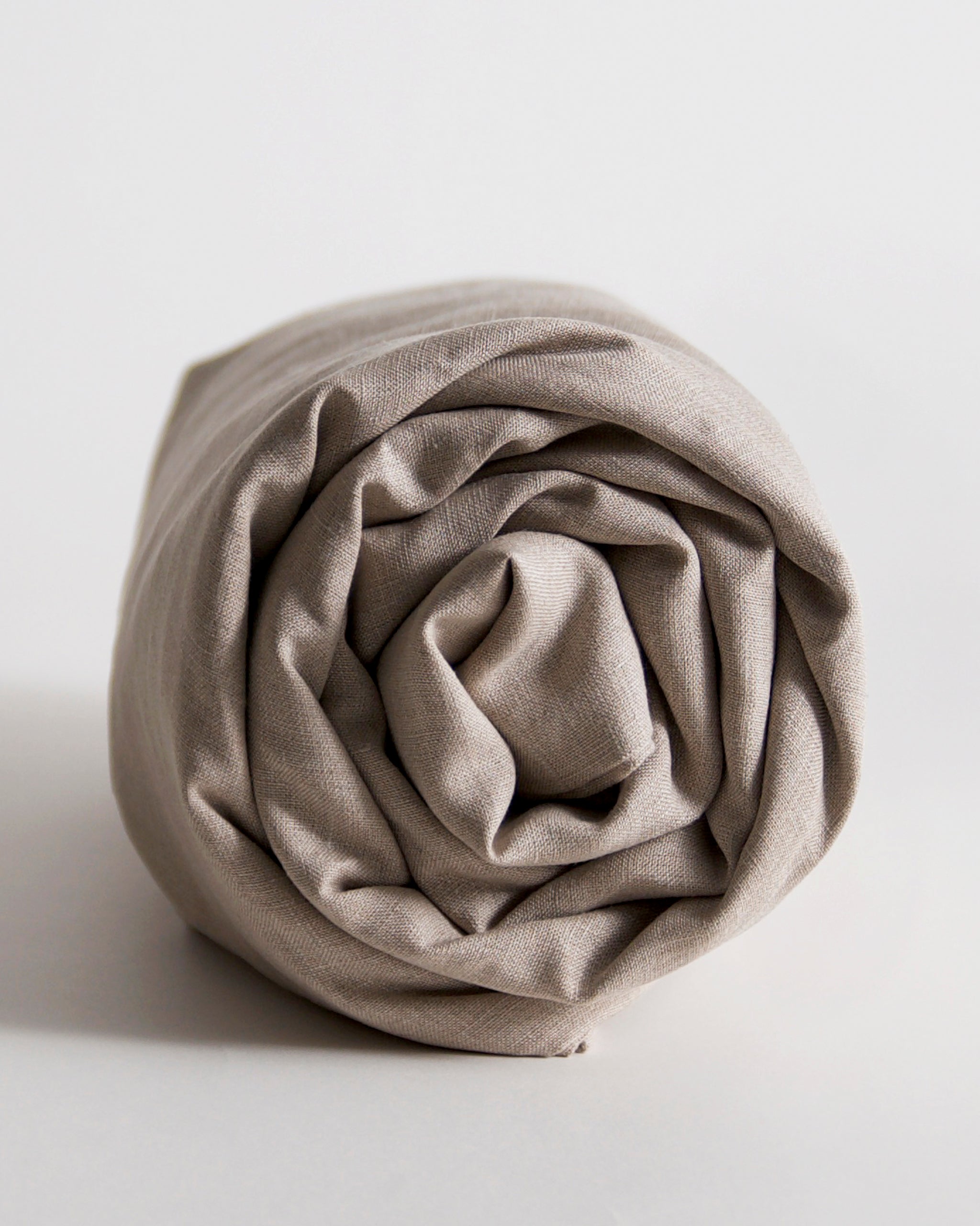 Rolled-up unbleached linen duvet cover by iwata on a gray background
