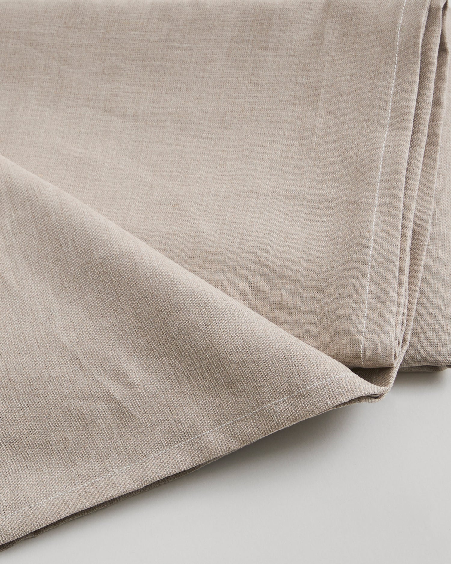 Close-up of unbleached linen sheet by Iwata on a light gray background