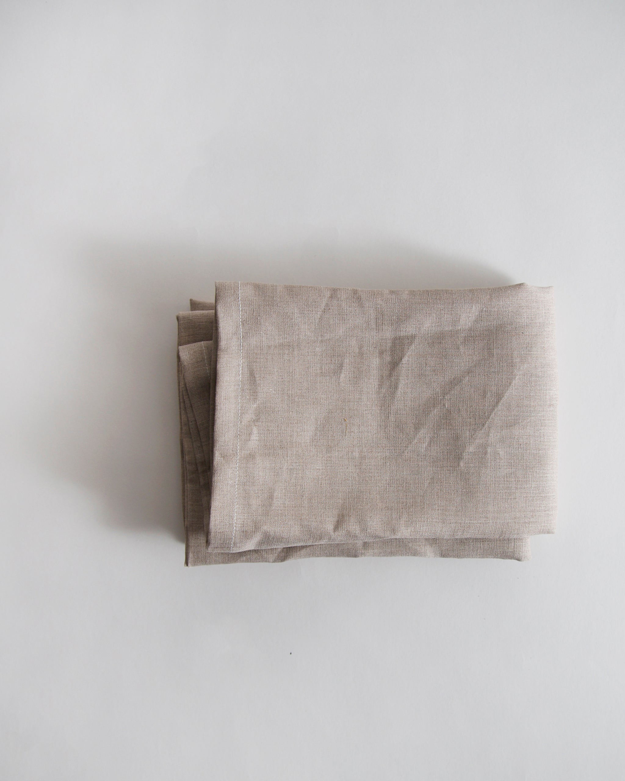 Folded unbleached linen pillowcase on a gray background