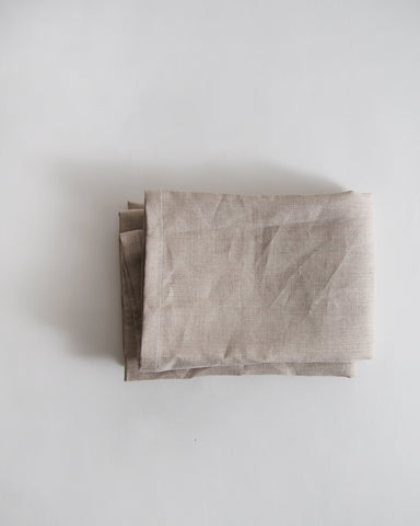 Folded unbleached linen pillowcase on a gray background