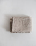 Folded unbleached linen pillow case by Iwata on a gray background